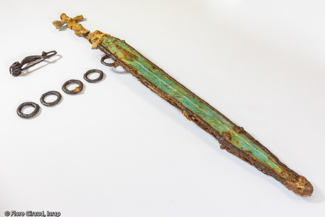 Mobilier métallique découvert dans la sépulture : fibule, anneaux de ceinture et épée.