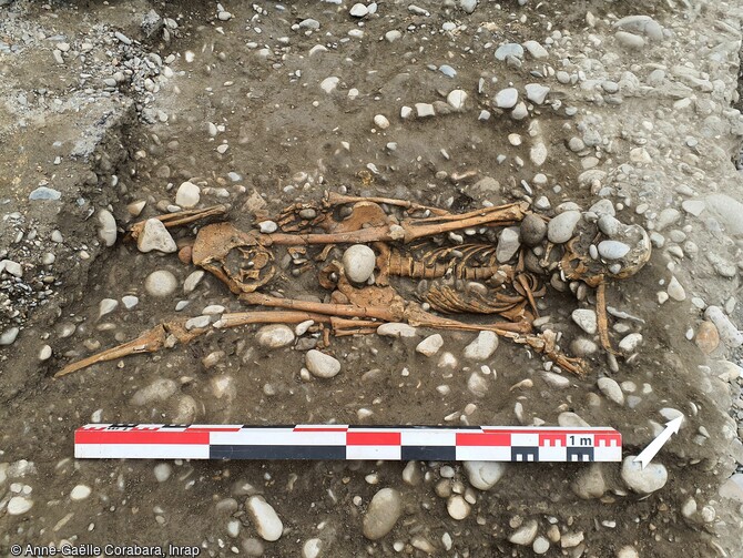 Déposition double avec un sujet sur le dos et un sujet sur le ventre.  Deux structures funéraires se démarquent nettement puisqu’elles associent des dépôts simultanés d’un nombre d’individus plus important. La structure plurielle, découverte au centre du bâtiment, associe à la fois des dépôts primaires en connexion, retrouvés sur plusieurs niveaux superposés et des restes osseux déconnectés retrouvés pêle-mêle, le tout dans un grand désordre.