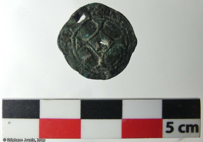Revers d'un Brûlé de Jean de Heinsberg (monnaie frappée entre 1434 et 1455) recueilli dans un niveau de remblai lié à la reconstruction de l'église Saint-Martin au XVe siècle à Montbéliard (Doubs).