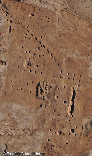 Vue aérienne de deux bâtiments allongés du Bronze final à Onnaing (Nord). Une vingtaine de bâtiments ont été révélé sur ce site dont plusieurs d'entre eux forment des constructions imposantes de plan rectangulaire de 25 m de long à terminaison en abside. La densité des structures fouillés, la présence de nombreux indices de constructions et l'étendue de leur répartition rendent ce site inédit en Hauts-de-France. Les vestiges témoignent d'une occupation débutant à l'âge du Bronze final et qui se poursuit jusqu'au début de l'âge du Fer. 