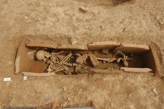 Inhumation en coffre à tuiles de la nécropole de Savasse (Drôme) datant du Bas-Empire (IVe et Ve siècles de notre ère), 2010.  Cette sépulture a livré une paire de semelles cloutées posée sur le défunt ainsi qu'un dépôt de céramiques à ses pieds, sans doute lié à un banquet funéraire. 