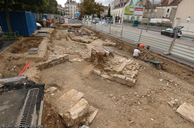 Fouille du rempart du XVIe s., vu de l'extérieur, avec une rigole d'évacuation en pierre taillée prise dans la maçonnerie, place de la République, Dijon (Côte-d'Or), 2010.  Du fossé remblayé émergent, au premier plan, les maçonneries d'une pile de l'ancien pont de la porte Saint-Nicolas. 