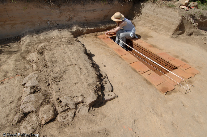 Sépulture à inhumation d’un enfant (8 - 9 ans) dans un caveau en briques (longueur 2,40 m, largeur 1 m), IIe-IIIe s. de notre ère, Neuville-sur-Sarthe (Sarthe), 2010.  A gauche se distingue une seconde tombe dont les limites sont matérialisées par des blocs de pierre. 