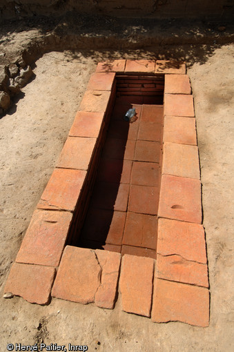 Sépulture à inhumation d’un enfant (8 - 9 ans) dans un caveau en briques (longueur 2,40 m, largeur 1 m), IIe-IIIe s. de notre ère, Neuville-sur-Sarthe (Sarthe), 2010.  La mise au jour d’une telle tombe dans l’enceinte sacrée d’un temple gallo-romain pose la question de leur éventuelle contemporanéité, en effet il est de règle à l’époque gallo-romaine de séparer ce qui est « pur » (les temples) de ce qui est « impur » (les inhumations par exemple).