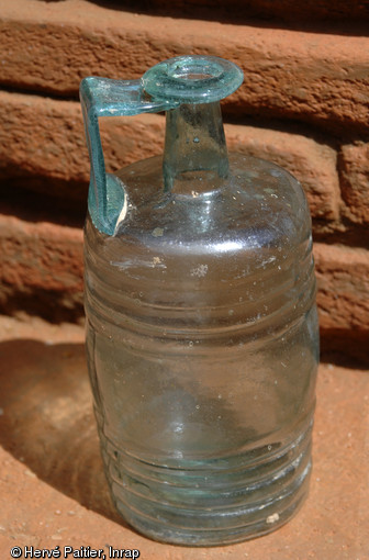 Petite bouteille en verre, intacte et de type  barillet frontinien , mise au jour dans la sépulture à inhumation avec caveau en briques, IIe-IIIe s. de notre ère, Neuville-sur-Sarthe (Sarthe), 2010. 