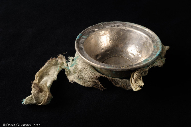 Coupe en alliage cuivreux recouvert d'une feuille d'argent, avec son tissu d'emballage, IIe-IIIe s. de notre ère, Reims (Marne), 2009.  Le dépôt d'argenterie mis au jour s'assimile à un service de qualité remisé soigneusement à la cave par son propriétaire. 