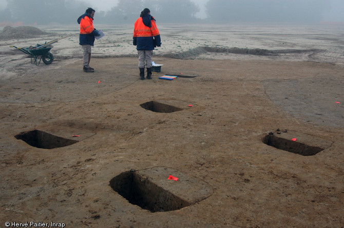 Fouille d'un grenier du second âge du Fer à Lamballe (Côtes-d'Armor), 2006-2007.  Les quatre structures au premier plan correspondent aux trous de poteaux sur lesquels s'élevait le bâtiment. 