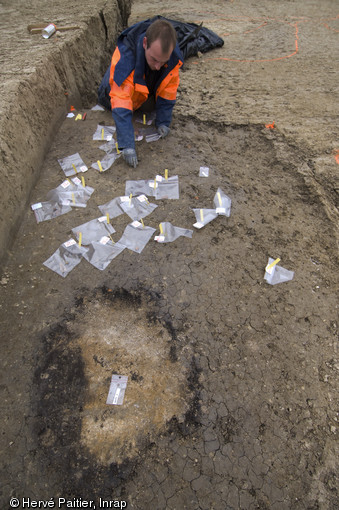 Les différentes structures archéologiques repérées après décapage sont numérotées et leurs emplacements marqués au sol afin qu'elles soient topographiées, fouille du site d'Alizay (Eure), 2011.  L'étude topographique permettra de mieux appréhender la succession des différentes phases d'occupation du site, occupé de manière régulière entre le Paléolithique supérieur et la fin de l'âge du Bronze.  