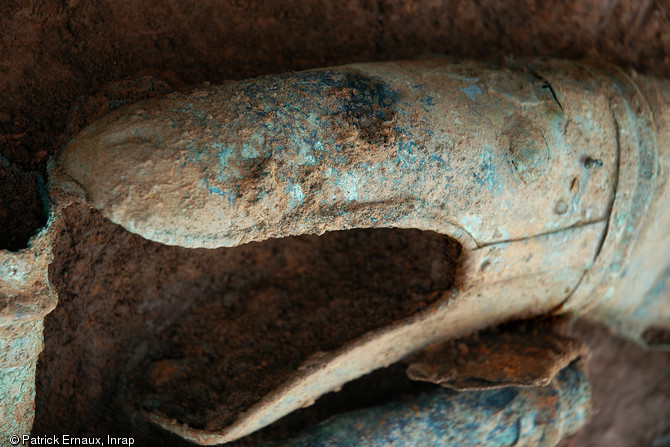 Pavillon du carnyx à tête de serpent dans la fosse dépotoir d'objets gaulois à Tintignac en Corrèze.  Cette portion de trompette de guerre est constituée de tôles en alliage cuivreux, rivetées entre elles.  Restauration Materia Viva