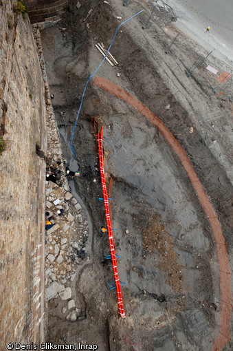 Vue aérienne de la fouille de la Tour Denis au Mont-Saint-Michel (Manche), 2011.  La tour est édifiée en 1420 et définitivement démolie en 1732. Pour réaliser cette fouille, la mise en place d'un épais merlon (à droite de la photo) a été nécessaire afin de la protéger des marées. 