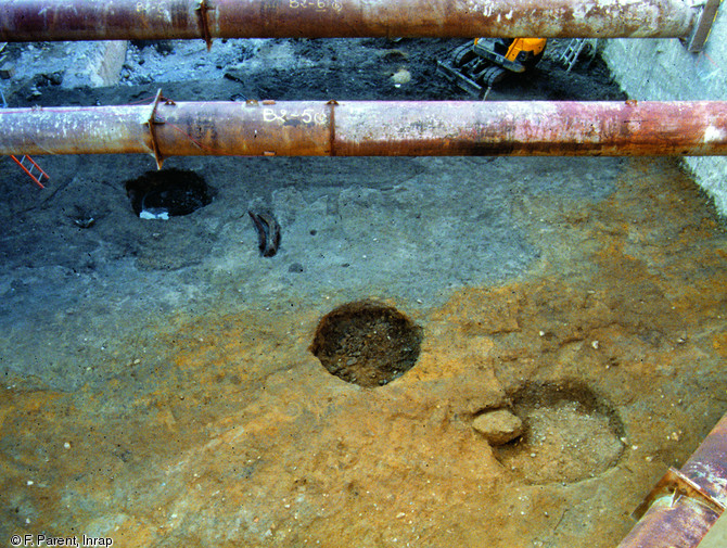 Niveau de plage du IVe s. avant notre ère, Marseille, 2005. La petite fosse entre les deux trous de poteaux du centre et de gauche abrite une membrure (élément du squelette de la coque d'un navire) : les plages accueillent des chantiers navals. La différence de couleur des sédiments dessine la ligne de rivage qui s'est déplacée vers le sud.    Photo publiée dans le numéro 20 de 