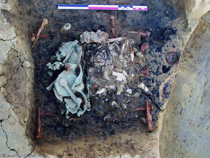 Tombe-bûcher de la première moitié du Ier s. de notre ère, mise au jour à Annecy (Haute-Savoie), 2005.  Après crémation du défunt, la fosse a été vidée afin de trier les résidus de crémation. Une partie seulement des os et du mobilier a alors été disposée dans un coffret octogonal en bois d'érable doté d'une serrure. Ce dernier a alors été placé dans une caisse cloutée en sapin.  Photo publiée dans le numéro 23 de la revue de l'Inrap <a class= rte-link-ext  href= http://www.inrap.fr/archeologie-preventive/La-Recherche/Archeopages/La-revue/p-9131-A-propos.htm  target= 