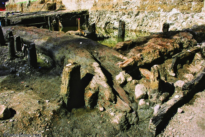 Caisson constitué de troncs flottés dans le soubassement du talus du rempart du XIVe s., Bordeaux, 2002-2003.  La sortie du fleuve des bois flottés permet de se procurer des matériaux de construction pour aménager les berges tout en réduisant les risques d'avaries sur les bateaux s'aventurant dans l'estuaire.  Photo publiée dans le numéro 29 de la revue de l'Inrap <a class= rte-link-ext  href= http://www.inrap.fr/archeologie-preventive/Recherche-scientifique/Archeopages/Les-numeros/28-29-30-HS02-2010/Numero-29/Dossier-Recyclage-et-remploi/p-11774-Le-port-lieu-de-recyc