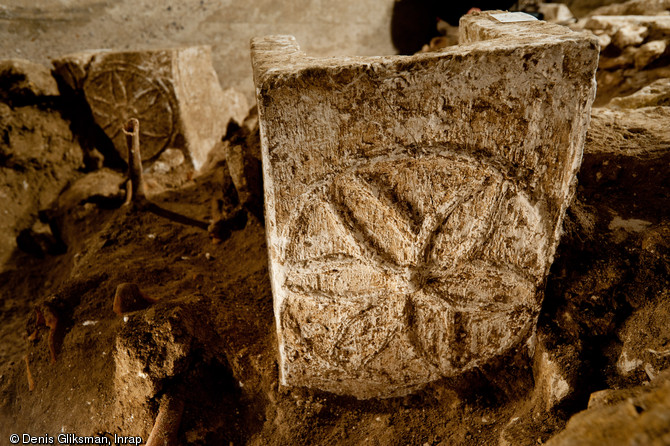 Panneau de pied d'un sarcophage mérovingien décoré d'une rosace mis au jour dans la partie est du chœur, église Saint-Pierre et Saint-Paul à Gonesse (Val-d'Oise), 2011.  On distingue à l'arrière-plan un autre panneau. 