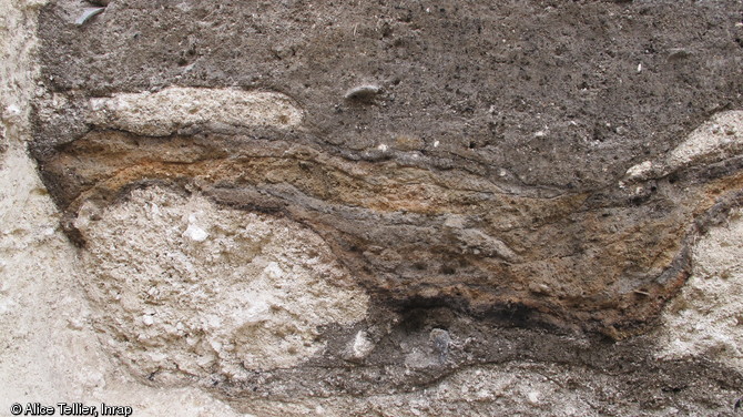 Vue de détail d'une coupe stratigraphique réalisée dans un silo daté de la première moitié du IIIe s. avant notre ère, Épieds-en-Beauce (Loiret), 2011.  La coupe montre les effondrements calcaires et surtout l'alternance entre les couches de rejets de foyer (céramique, faune...) et celles de cendre. 