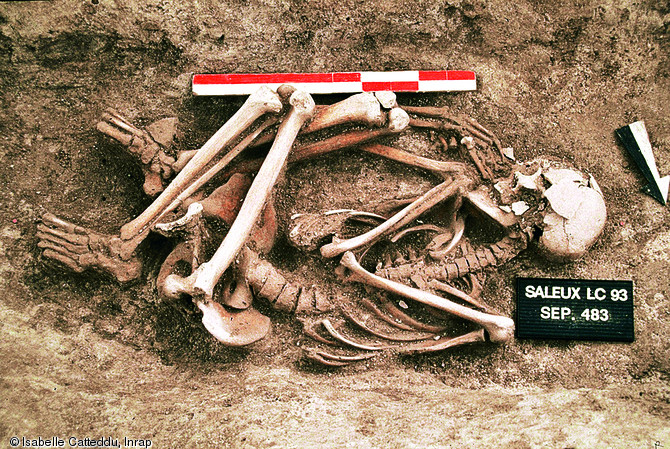 Squelette en position fœtale découvert dans un fossé de l'habitat médiéval de Saleux (Somme), 1993.  Cet individu fait partie des six défunts exclus de l'espace funéraire de l'établissement et isolés dans les fossés de l'habitat.  Photo publiée dans l'ouvrage Archéologie médiévale en France - Le premier Moyen Âge, Isabelle Catteddu, coll. Archéologies de la France. 