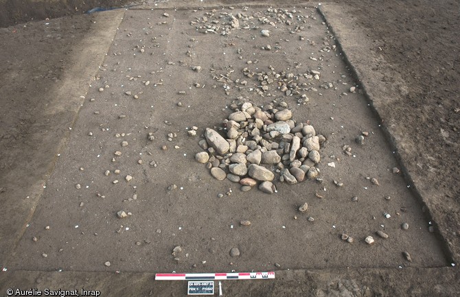 Niveau de sol du Néolithique moyen chasséen (3900-3700 avant notre ère) avec au premier plan un foyer à pierres chauffées et au second plan deux fosses de rejet, Cournon-d'Auvergne (Puy-de-Dôme), 2011.La présence de sols d'occupation denses, structurés et remarquablement conservés comme celui-ci a justifié le classement du site comme découverte d'importance exceptionnelle.