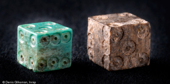 Deux d&eacute;s &agrave; jouer m&eacute;di&eacute;vaux mis au jour dans les couches du chantier de construction de la cath&eacute;drale de Strasbourg (Bas-Rhin), 2012.  Le jeu de d&eacute;s constitue un moment de pause dans les journ&eacute;es de travail des b&acirc;tisseurs. 