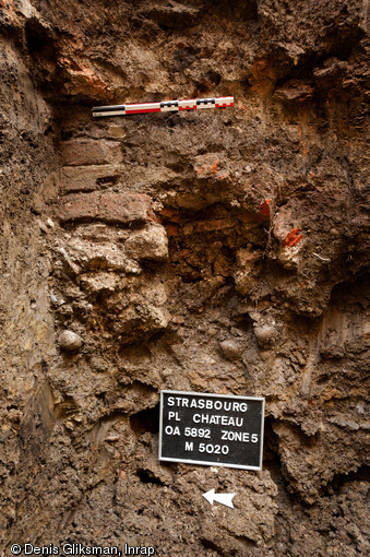 Vue d'un mur observ&eacute; en suivi de r&eacute;seau dans une tranch&eacute;e creus&eacute;e place du Ch&acirc;teau &agrave; Strasbourg (Bas-Rhin), 2012.  La structure est un angle de b&acirc;timent dont la base de la ma&ccedil;onnerie est constitu&eacute;e de tuiles romaines plates &agrave; rebord (tegula) superpos&eacute;es les unes sur les autres. 