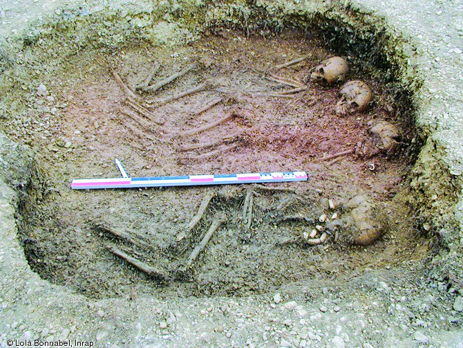 Sépulture simultanée de trois individus suivie de l'inhumation plus tardive d'un quatrième corps dans une nouvelle fosse de couleur plus grise, Écriennes (Marne).  Les trois premiers corps ont été déposés simultanément dans l'ordre suivant : l'adulte de sexe féminin, l'enfant le plus âgé et l'enfant le plus jeune.  Photo publiée dans l'ouvrage Archéologie de la mort en France, Lola Bonnabel, coll. Archéologies de la France. 