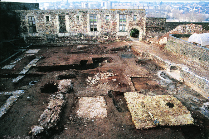 Vue générale des jardins du quadrilatère du château d'Angers (Maine-et-Loire) en cours de fouille, 1997.  Au premier plan apparaissent les massifs de fondation d'un temple antique des Ier-IIIe s. de notre ère. En arrière-plan on distingue la façade est du mur oriental de la aula des Xe-XIIe s. d'où se dégagent le portail en plein cintre du palais comtal et les grandes baies de la résidence.  Photo publiée dans le numéro 19 de la revue de l'Inrap <a class= rte-link-ext  href= http://www.inrap.fr/archeologie-preventive/Recherche-s