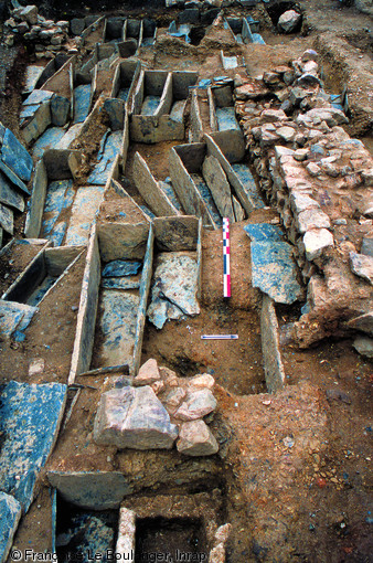 Sépultures en coffre dans une chapelle funéraire utilisée entre le VIIe et la fin du XIe s., Bréal-sous-Vitré (Ille-et-Vilaine), 2003.Au total, 64 coffres en schiste ardoisier ont été dégagés, renfermant de multiples réductions et autres os surnuméraires, attestant d'une gestion soignée de l'espace funéraire et d'ouvertures successives des coffres pour procéder à de nouvelles inhumations.    Photo publiée dans le numéro 19 de la revue de l'Inrap<a class= rte-link-ext  href= http://www.inrap.fr/archeologie-preventive/Recherche-scientifique/A