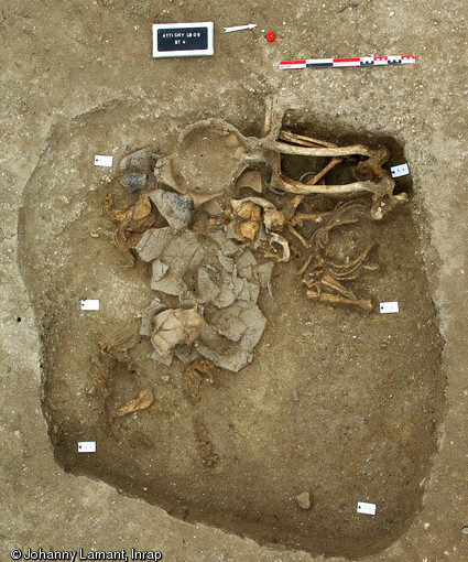 Vue g&eacute;n&eacute;rale de la s&eacute;pulture d'un homme  pli&eacute; , IIIe&nbsp;s. avant notre &egrave;re, Attichy (Oise), 2009.L&rsquo;homme d&rsquo;&acirc;ge adulte est d&eacute;pos&eacute; sur le dos en position f&oelig;tale, le regard orient&eacute; vers le septentrion, le corps d&eacute;cal&eacute; de 90&deg; par rapport &agrave; la pratique &laquo; admise &raquo; au sein de cette n&eacute;cropole. Malgr&eacute; cette singularit&eacute;, on note un rituel similaire aux autres s&eacute;pultures avec la pr&eacute;sence de tr&egrave;s nombreuses offrandes alimentaires.