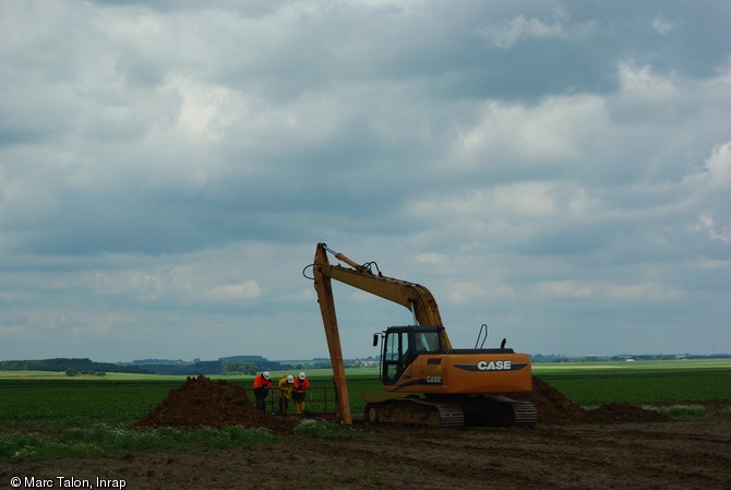 Campagne de sondages profonds avec utilisation d'une pelle hydraulique &agrave; bras rallong&eacute; sur le trac&eacute; du Canal Seine-Nord Europe dans le Pas-de-Calais en 2009.  Le balcon-passerelle permet aux arch&eacute;ologues de se pencher sans danger pour observer et relever la stratigraphie. Ce type de pelle permet de r&eacute;aliser des sondages en puits jusqu'&agrave; 14 m de profondeur.