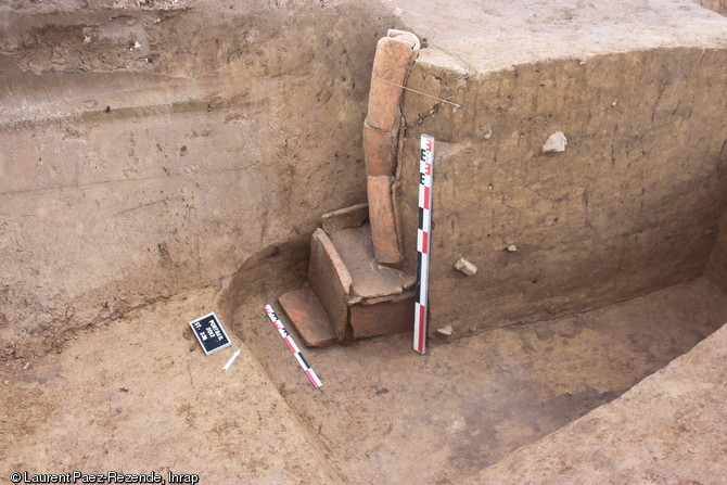 Tombe à libations en cours de dégagement, Ier-IIIe s. de notre ère, Portbail (Manche), 2012.La fouille a fait apparaître un conduit à libations construit au moyen d'un assemblage d'imbrices (tuiles arrondies, ou  canal ) placées deux à deux sur trois niveaux. Le conduit débouche sur le coffrage en tuiles de la sépulture.