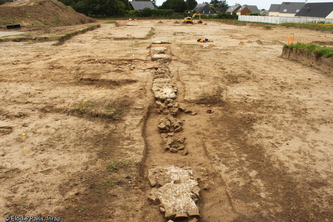 Les fondations du péristyle de la domus ou de l'établissement thermal en cours de dégagement, Ier-IIIe s. de notre ère, Portbail (Manche), 2012.Cette construction est rythmée par d'imposants massifs régulièrement espacés, destinés à supporter une colonnade. Dans les intervalles, des fondations plus étroites marquent l'emplacement de murets bas reliant les colonnes.  