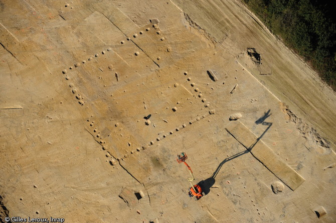 Vue aérienne de bâtiments gallo-romains à Brielles (Ille-et-Vilaine), 2011.Des tâches sombres dessinent au sol le plan carré d’une vaste construction d’environ 500 m2. Il s’agit de fosses autrefois creusées pour accueillir les poteaux, aujourd’hui disparus, utilisés pour l’architecture d’un vaste bâtiment, sans doute destiné à l’élevage. Celui-ci était un des éléments de la partie agricole (ou pars rustica) d’une villa gallo-romaine.