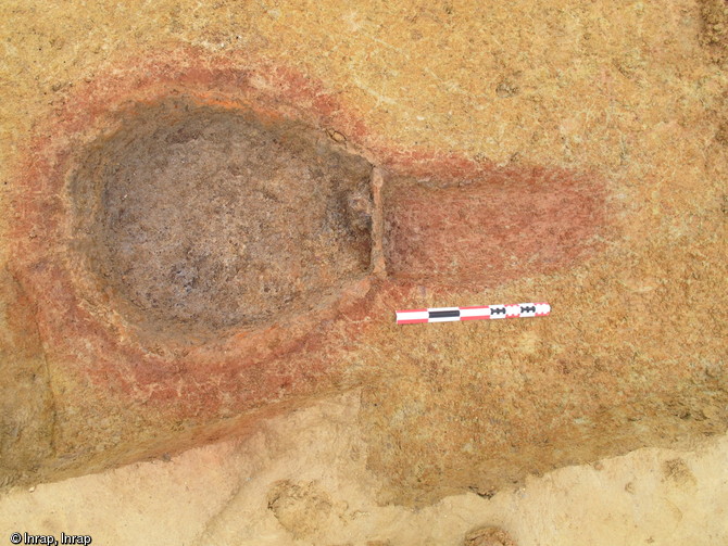 Vue zénithale d'un des fours du second atelier gaulois de réduction de minerai de fer mis au jour à la Mare, La Milesse (Sarthe), 2012.De gauche à droite on observe la cuve, les restes de la porte et la tranchée d'accès au four.