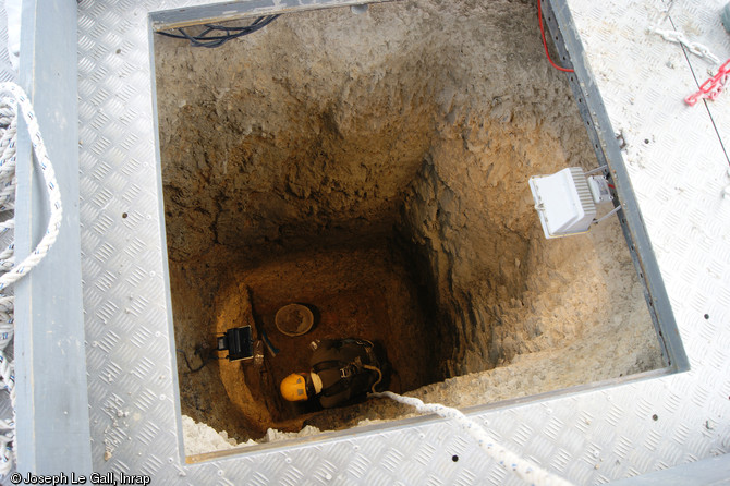 Fouille au fond d'une citerne d&eacute;couverte &agrave; la Claraiserie, IIe&nbsp;s. avant notre &egrave;re - Ier&nbsp;s. de notre &egrave;re, Oss&eacute; (Ille-et-Vilaine), 2013.De plan carr&eacute;, la citerne pr&eacute;sente une profondeur de 4 m. Un cuvelage en bois devait &ecirc;tre am&eacute;nag&eacute; sur sa paroi int&eacute;rieure.&nbsp;