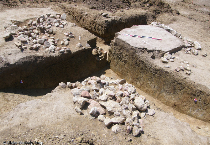 Bâtiment sur solin de pierre des XIIe-XIIIe s. en cours de fouille, La Quinte (Sarthe), 2012.Au tournant du XIIe et du XIIIe s., le carrefour de voies à proximité du site des Chauvrières se décale d'une centaine de mètres vers l'ouest. La portion abandonnée d'un chemin creux a alors été investie par les occupants du lieu et deux bâtiments y ont été construits.