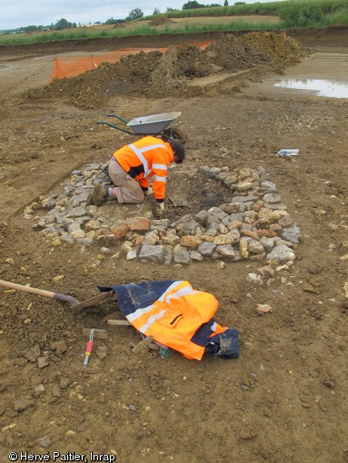 Fouille d'un des deux fours à chaux bien conservés sur le site, Vallon-sur-Gée (Sarthe), 2012.Il est formé d’un empierrement carré avec, en son centre, une chambre de chauffe circulaire. Les datations radiocarbones effectuées sur des prélèvements de charbon de bois indiquent que les fours ont été en usage vers la fin du Ier s. de notre ère.