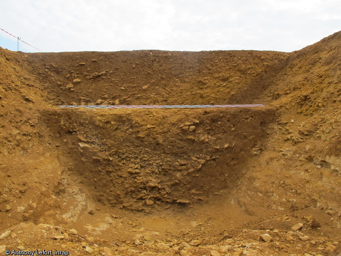 Vue en coupe de la branche est du foss&eacute; de l'enclos monumental de la place forte gauloise de Bourgu&eacute;bus (Calvados), 2013.L'am&eacute;nagement de tels foss&eacute;s a n&eacute;cessit&eacute; le recours &agrave; une main d'oeuvre consid&eacute;rable : creus&eacute;s dans la roche sur plusieurs centaines de m&egrave;tres, les plus grands atteignent 4 m de profondeur pour 6 m de large. &nbsp;