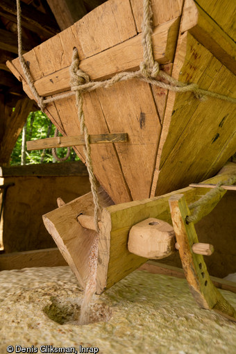 Le frottement du babillard sur la meule permet la vibration du bec de la trémie et facilite le glissement des grains vers la meule, moulin de Guédelon (Yonne), 2014.Les moulins mis au jour à Thervay (Jura), modèles pour la construction de celui de Guédelon, présentent des caractéristiques qui indiquent d’importantes évolutions dans les techniques et les capacités de mouture entre la période carolingienne et les XIe et XIIe s.