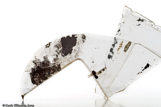 Fragment de cockpit en plexiglas d'un planeur Horsa. Une fibre de tissu en toile de jute est encore fix&eacute;e sur le plexiglas, ainsi qu'une charni&egrave;re m&eacute;tallique qui permettait d'ouvrir le cockpit. Datant du jour J de la Bataille de Normandie (nuit du 5 au 6 juin 1944) et d&eacute;couvert dans un trou d'homme &agrave; Ranville (Calvados), 2009.
