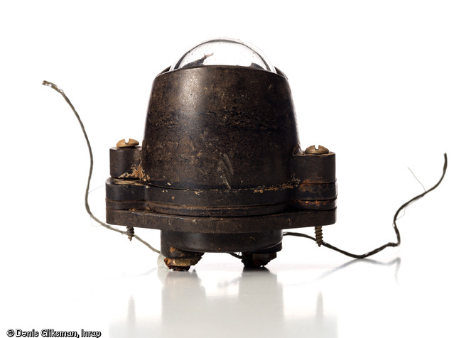 Ampoule et son support en bak&eacute;lite d'un feu de position de queue de planeur Horsa de la Royal Air Force (h. 7,4 cm), avec les vis et les c&acirc;bles d'alimention &eacute;lectriques encore en place. Datant du jour J de la Bataille de Normandie (nuit du 5 au 6 juin 1944) et d&eacute;couvert dans un trou d'homme &agrave; Ranville (Calvados), 2009.