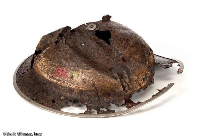 Casque d'acier britannique mod&egrave;le  Mark II  de Beach Groups en dotation au cours de la Seconde Guerre mondiale. Sa forme particuli&egrave;re le fait surnommer le  plat &agrave; barbe  et malgr&eacute; son &eacute;tat, il conserve encore un profil reconnaissable ainsi que des bandes de peinture d'identification encore visibles (d.30cm). D&eacute;couvert &agrave; Saint-Aubin-d'Arquenay (Calvados), 2013.