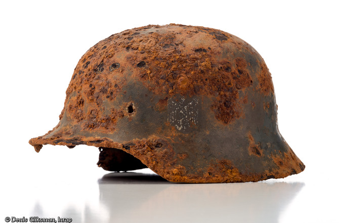 Casque allemand en acier (stahlhelm), mod&egrave;le 1935 (d. 25 cm et h. 25 cm), marqu&eacute; d'un &eacute;cusson avec une croix gamm&eacute;e. Ce casque a re&ccedil;u une peinture anti-reflet, probablement appliqu&eacute;e par le soldat sur le terrain. Datant de la Bataille de Normandie (&eacute;t&eacute; 1944) et d&eacute;couvert &agrave; Troarn (Calvados), 2009.