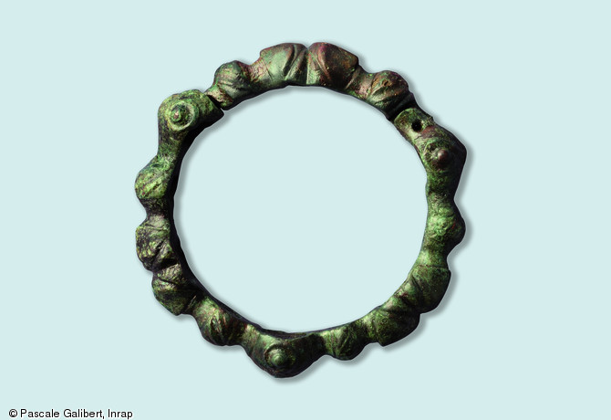 Objet de parure : bracelet articul&eacute; en alliage cuivreux, &agrave; d&eacute;cor de bossettes et de masques.