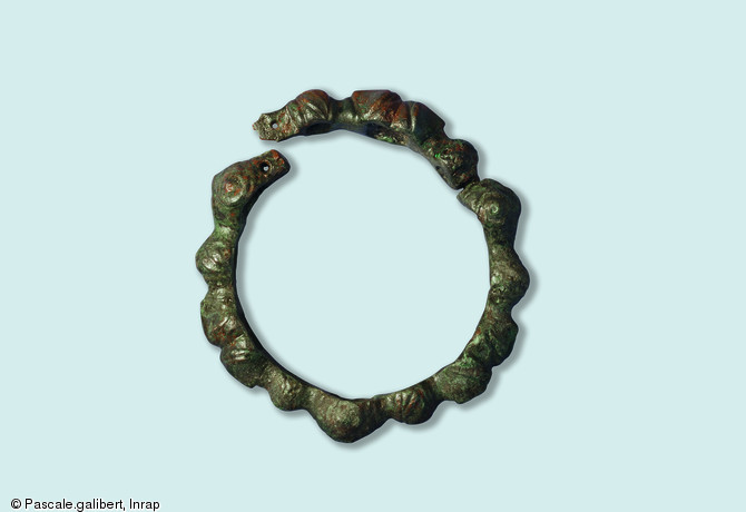 Objet de parure : bracelet articul&eacute; en alliage cuivreux, &agrave; d&eacute;cor de bossettes et de masques.