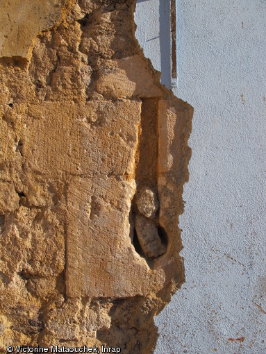 Détail sur une archère-canonnière de l'enceinte de la basse-cour de l'abbaye Saint-Pierre, début XVe siècle, masquée sous les enduits en ciment récent et découverte pendant les travaux de démolition, à Méobecq (Indre), 2012. 