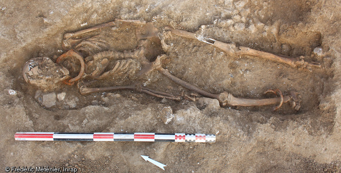 S&eacute;pulture 2073 en cours de fouille. Individu masculin inhum&eacute; en d&eacute;cubitus, entrav&eacute; au cou et &agrave; la cheville droite, d&eacute;couvert dans une n&eacute;cropole antique &agrave; Saintes (Charente-Maritime).  L'entrave du cou se compose de 2 parties, termin&eacute;es par un  oeil  &agrave; l'une des extr&eacute;mit&eacute;s, ce qui permet la mobilit&eacute; des deux brins.  Celle de la cheville d'un anneau en fer ferm&eacute; par enroulement. Les 2 extr&eacute;mit&eacute;s du jonc sont solidaris&eacute;es par rivetage. Un second anneau a &eacute;t&eacute; pass&eacute; dans l'entrave avant sa fermeture. Ce m&eacute;canisme est donc inamovible et seule une d&eacute;coupe permet de lib&eacute;rer l'individu. 