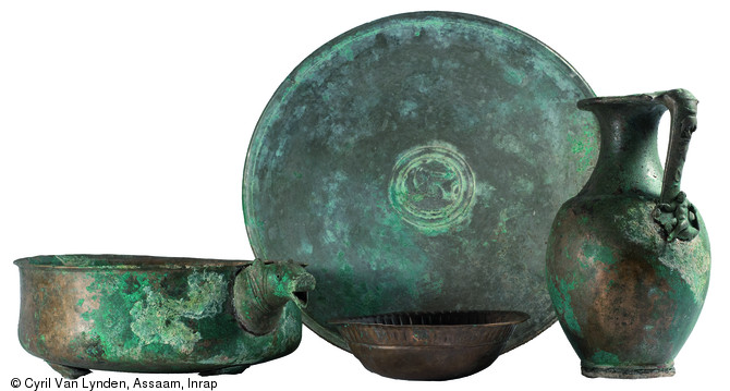S&eacute;lection de quatre pi&egrave;ces d'un service &agrave; vin en alliage cuivreux du IIIe si&egrave;cle de notre &egrave;re. D&eacute;couvert dans un grand chaudron d'environ 0,80 m de diam&egrave;tre qui contenait 13 objets sur le site d'Argentomagus &agrave; Saint-Marcel (Indre), 2013.  De gauche &agrave; droite : un bassin, un grand plat, une coupelle et un pot. 