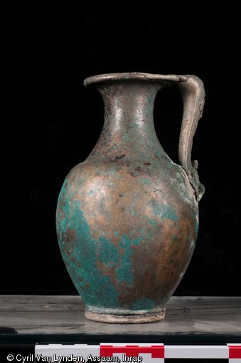 Pot en alliage cuivreux comportant une anse orn&eacute;e d'une sc&egrave;ne mythologique, repr&eacute;sentant sur la partie inf&eacute;rieure, Hercule se reposant sur sa massue et sur la partie sup&eacute;rieure, son fils T&eacute;l&egrave;phe accompagn&eacute; d'une biche. Pi&egrave;ce d'un service &agrave; vin du IIIe si&egrave;cle de notre &egrave;re, d&eacute;couvert sur le site d'Argentomagus &agrave; Saint-Marcel (Indre), 2013. 