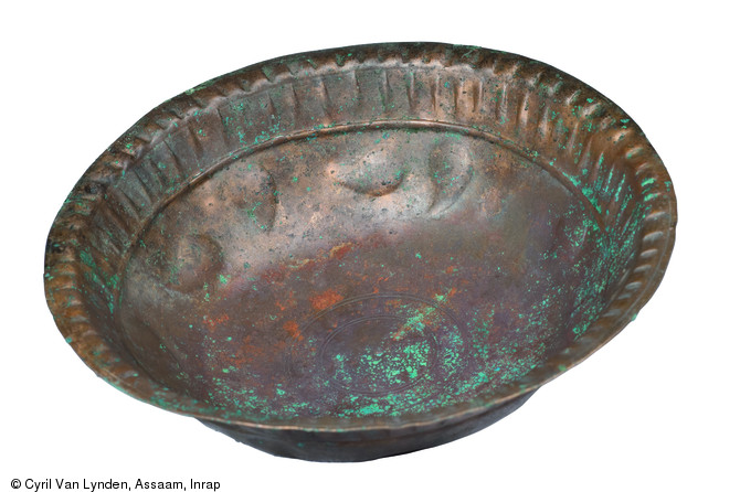 Coupelle en alliage cuivreux d&eacute;cor&eacute;e d'une s&eacute;rie de gouttes ou de feuilles d'eau surmont&eacute;e par un ligne en relief. Au dessus de cette ligne, une frise de moulures obliques qui donne naissance &agrave; un bord plus ou moins perl&eacute;. Pi&egrave;ce d'un service &agrave; vin du IIIe si&egrave;cle de notre &egrave;re, d&eacute;couvert sur le site d'Argentomagus &agrave; Saint-Marcel (Indre), 2013.